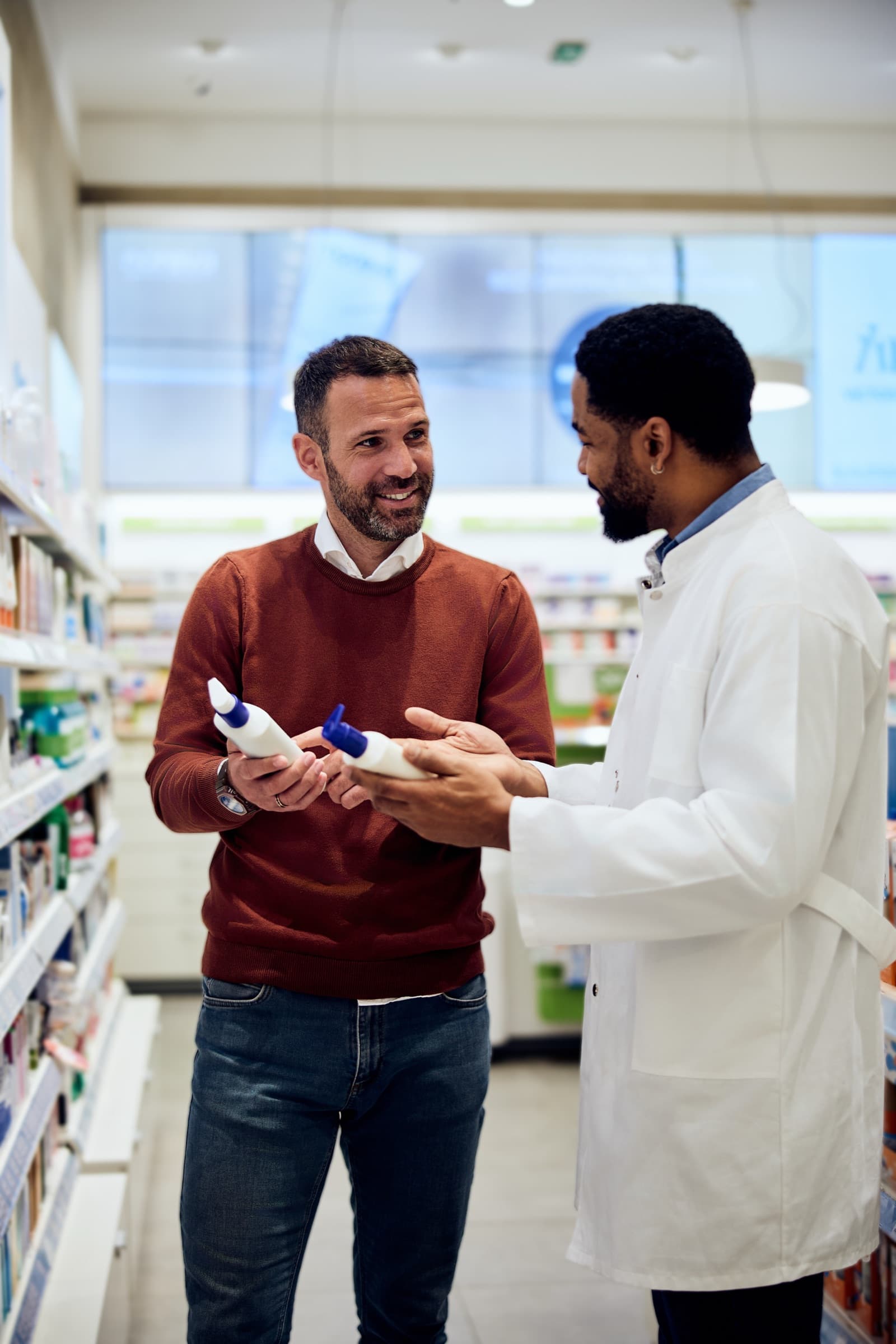 A pharmacist consulting with a patient in a pharmacy aisle